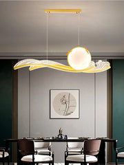 Modern pendant light hanging above a dining table with a neutral wall and framed artwork in the background.