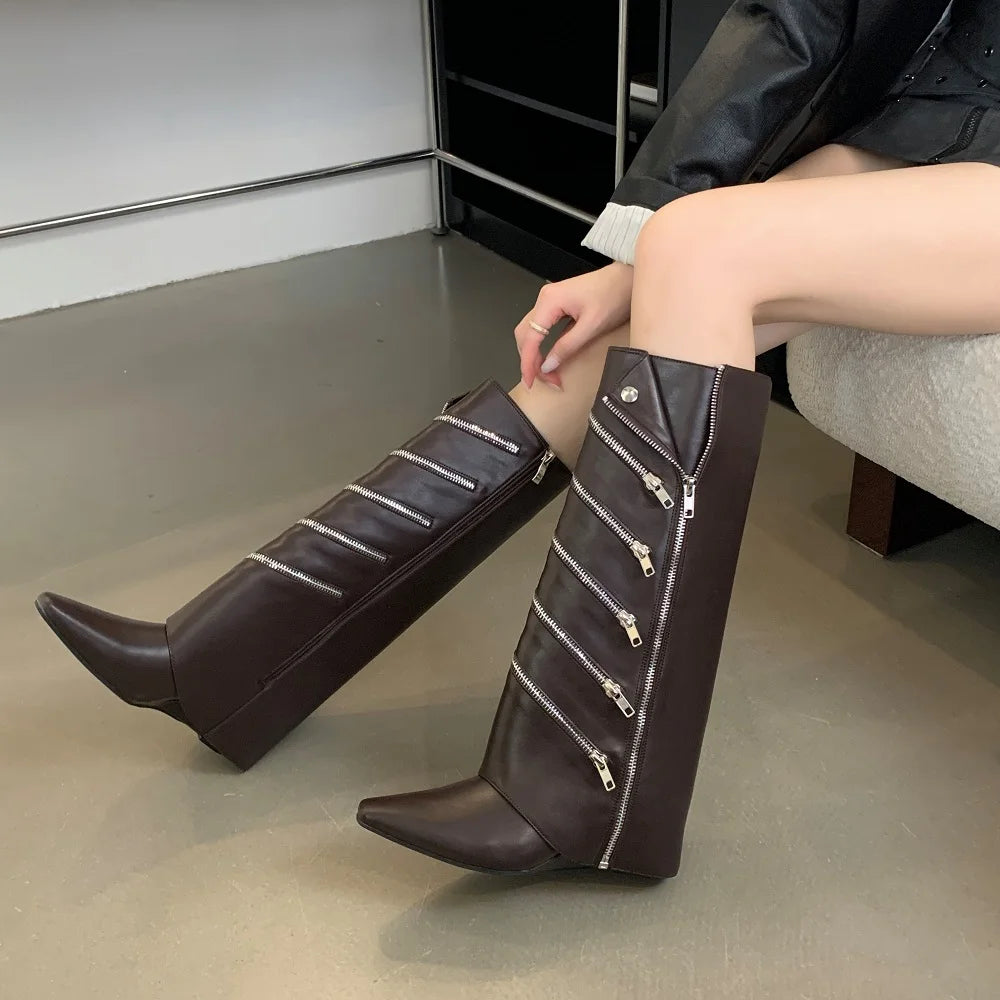 Brown knee-high boots with zippers worn by a person sitting on a chair.
