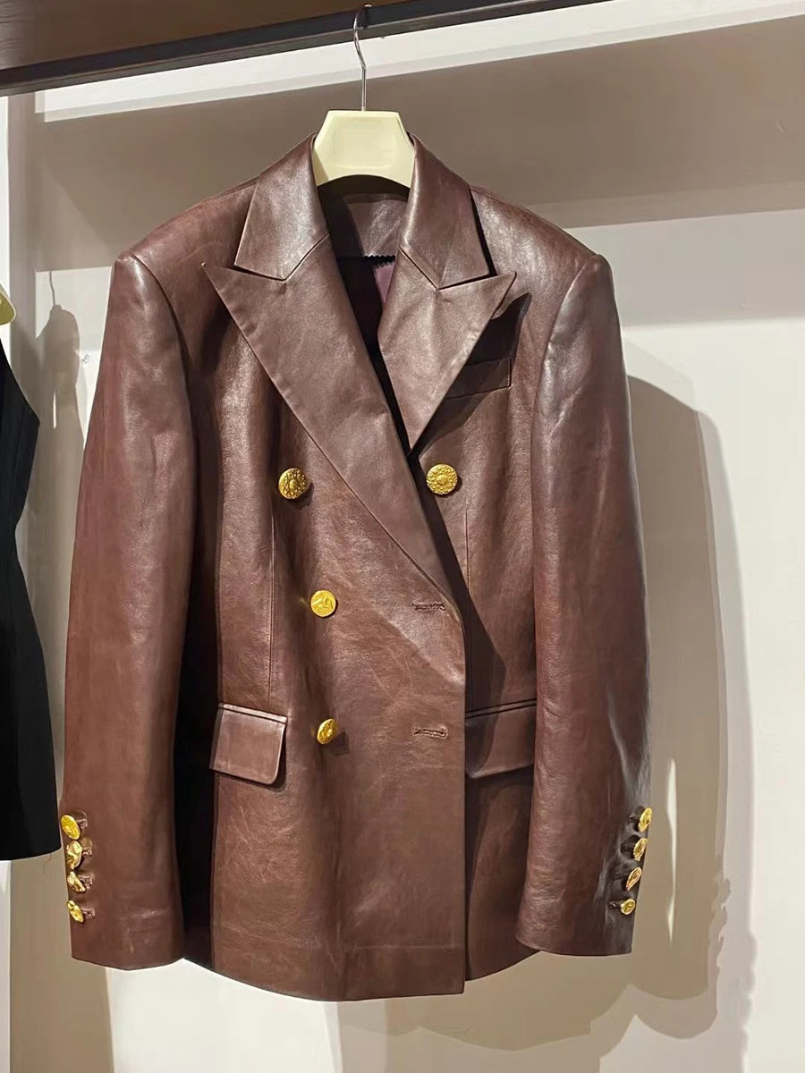 Brown leather jacket with gold buttons on a hanger against a white wall.