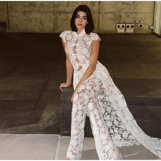 Woman wearing a white lace mock neck sleeveless top and wide leg pants sitting