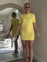 Woman wearing a yellow dress standing in front of a mirror.