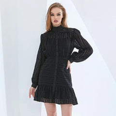 A female model wearing a black, solid colour, full sleeves high neck mini dress with a hollow-out decoration.