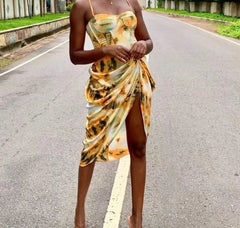  Golden Atelier tie-dye sundress with a relaxed silhouette and spaghetti straps. The dress features a colorful tie-dye pattern and is modeled on a woman in a summery setting. Yellow