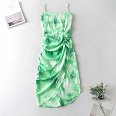  Golden Atelier tie-dye sundress with a relaxed silhouette and spaghetti straps. The dress features a colorful tie-dye pattern and is modeled on a woman in a summery setting. Green