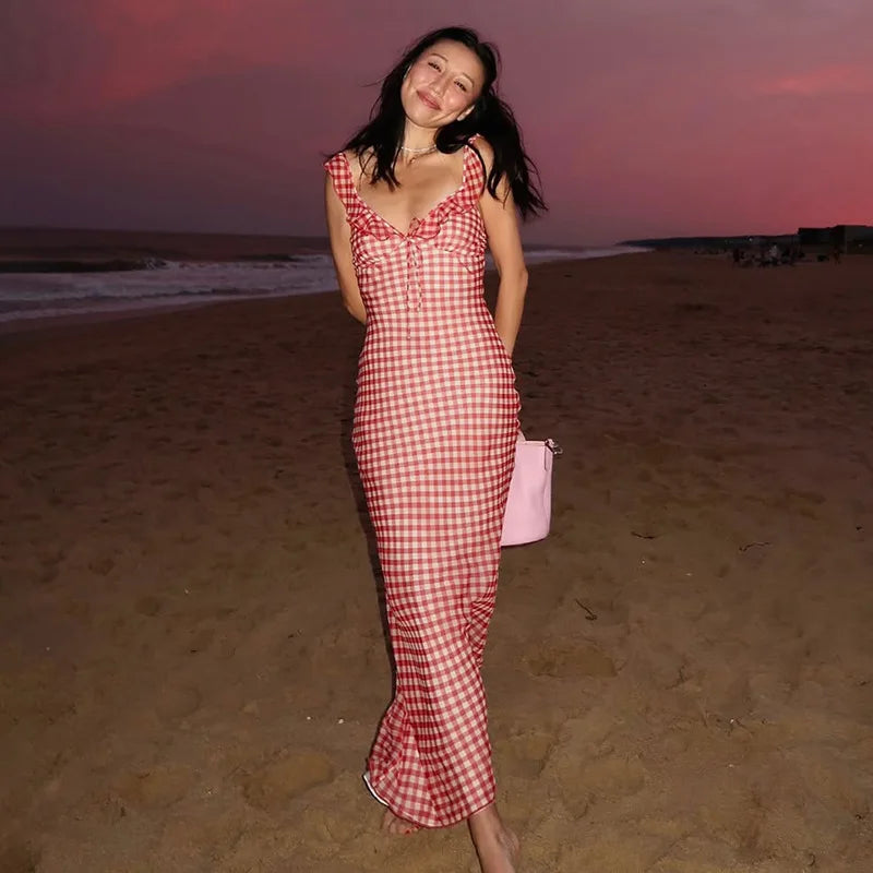 Woman in a Ankle-length gingham sundress perfect for warm-weather events standing on a beach at sunset.