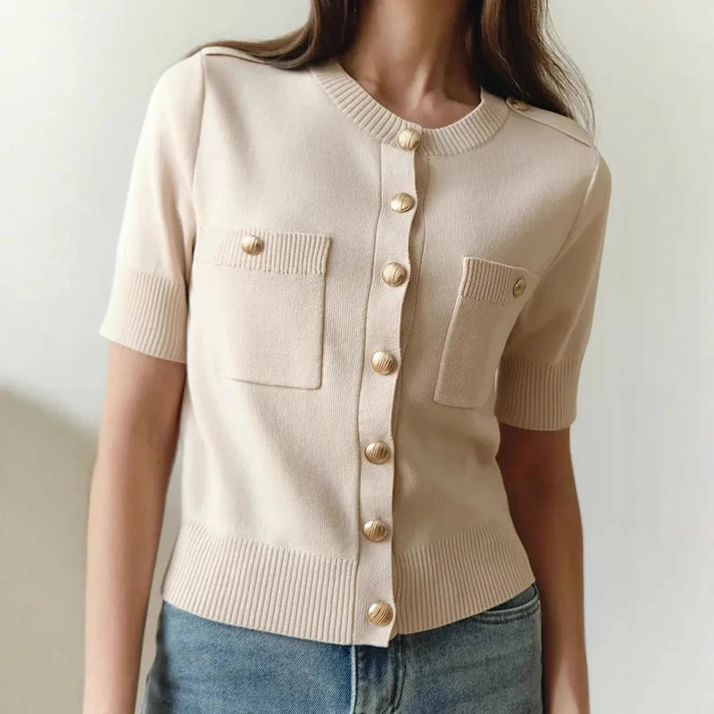 Apricot knit top with gold buttons worn by a model on a plain background