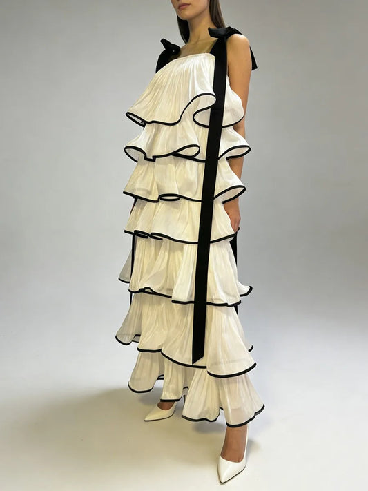 Side profile of tiered ruffle ankle length dress with graphic edge trim and sculpted A-line shape captured in motion on studio background