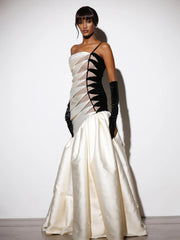 Asymmetric evening gown with patchwork fold details for luxury occasions .  A woman wearing a white and black evening gown with a plain background 