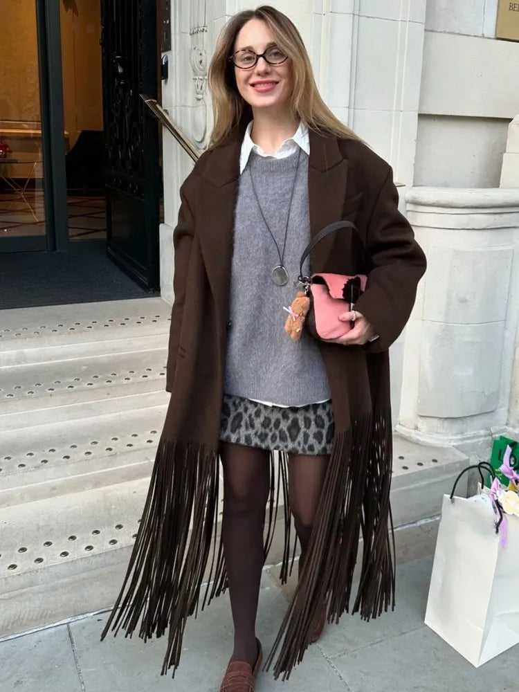 Front view showing the asymmetric hemline and fringe density on the brown trench coat, creating a dramatic, fashion-forward silhouette.