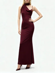 Full-length studio view of a model wearing an asymmetrical sheath dress with a clean ankle-length drape and minimalist evening posture.