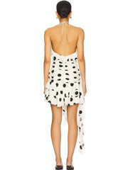 Back side view of a woman wearing a polka dot dress with a white background.
