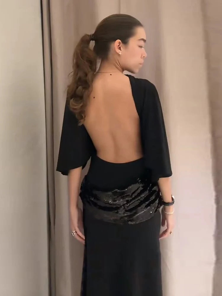 Back view of a black open-back mermaid dress, revealing the elegant cut and smooth fabric fall.