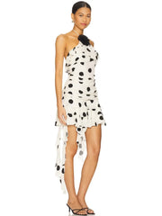 Woman wearing a dotted mini dress styled with strappy sandals for party nights on a white background