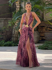 Woman in a  backless halter evening dress styled with metallic heels with a high slit standing outdoors.