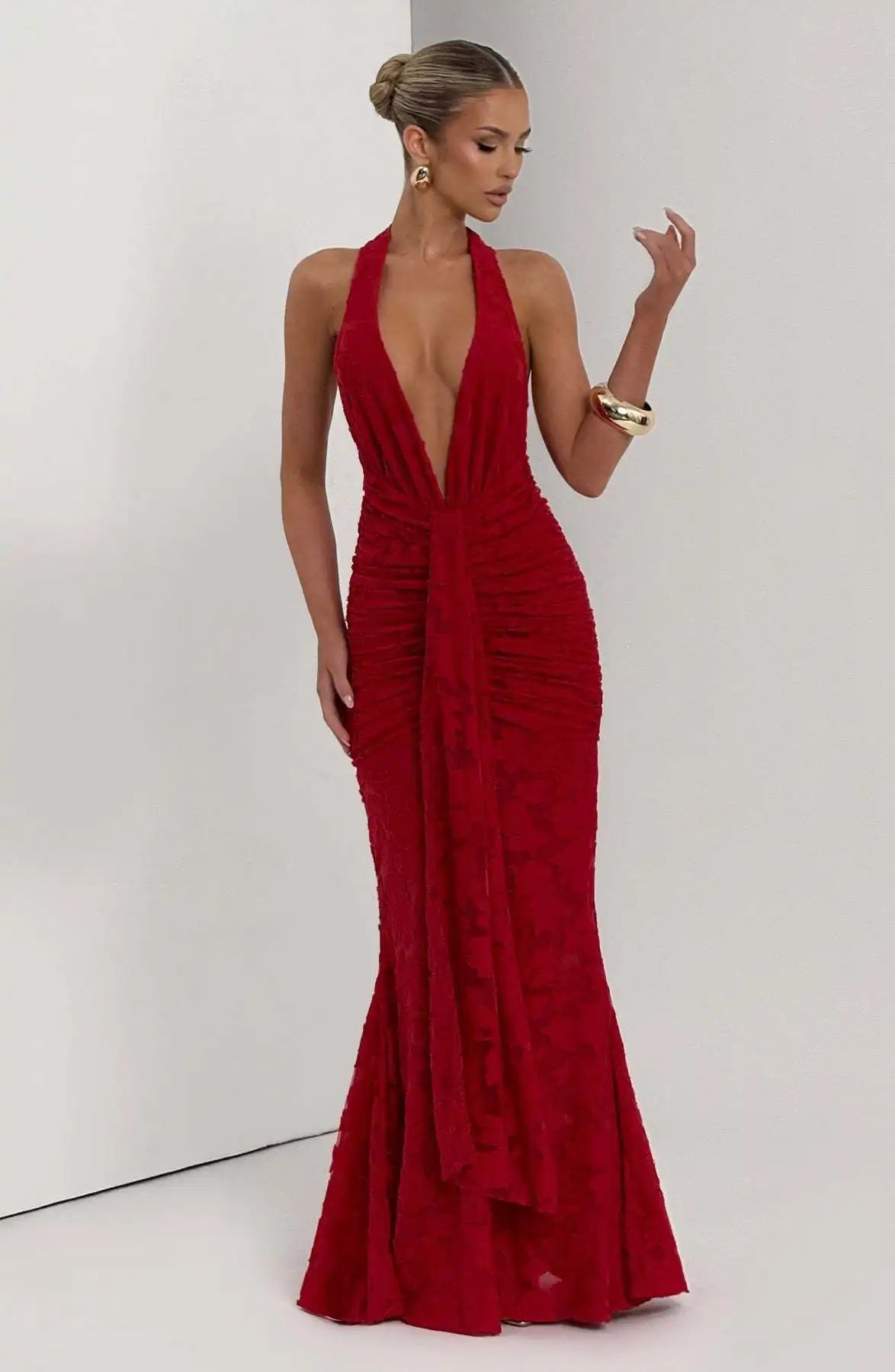 Woman wearing a red halter neck gown against a white background
