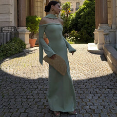 Woman in a light green dress standing on a cobblestone path with classical architecture in the background.