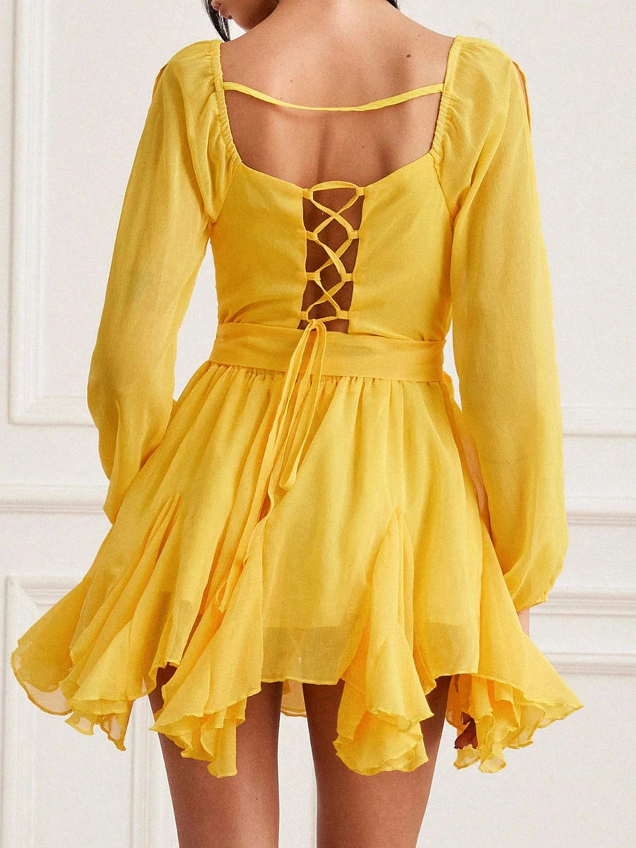 Back view of playful short yellow dress with asymmetric hem and relaxed fit on a white background .