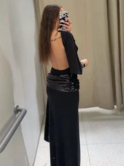 Side angle of a black batwing-sleeve maxi dress showing fluid drape and defined waist styling.