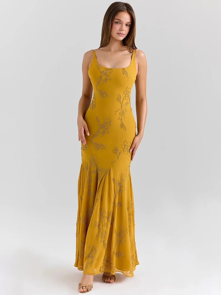 Woman wearing a mustard yellow dress with floral patterns on a white background