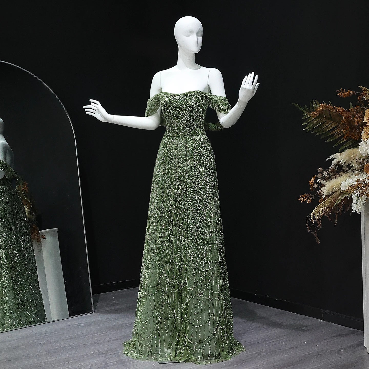 A mannequin wearing an elegant off-shoulder beaded tulle gown for a formal event.