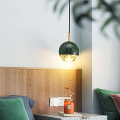 A  modern pendant light with marble and copper finishes,  suspended from the ceiling. Hanging beside a dinner table.