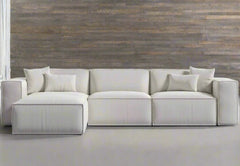 A beige modular combination porter sectional sofa with multiple cushions, displayed in a bright and spacious room with a stone wall finish.