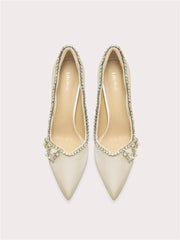Beige pointed-toe silk pumps with crystal trim along the opening