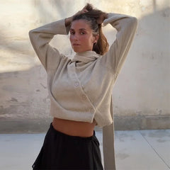 A woman wearing a bevel buckle asymmetric cardigan in a chic, modern style.

