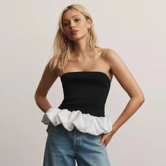 Woman wearing a black and white strapless ruffle top with blue jeans