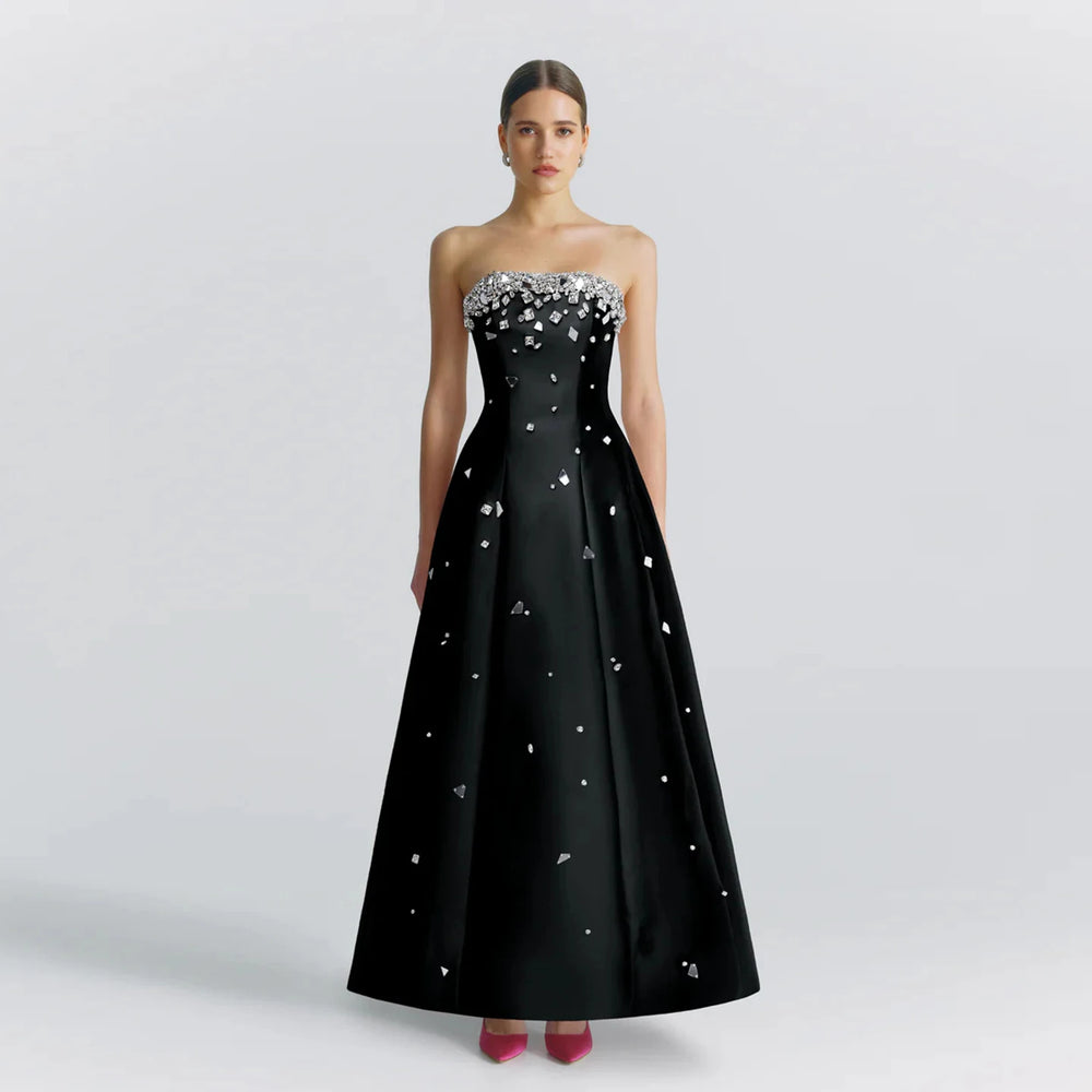 A woman wearing a black beaded satin evening gown styled for a formal event.