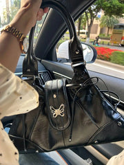 Black tote bag with butterfly appliqué, held inside a car
