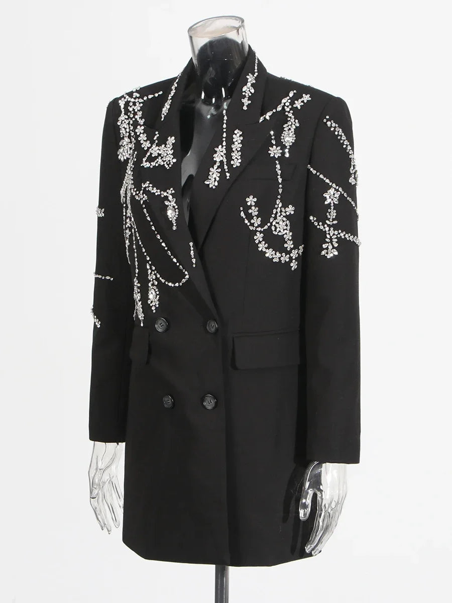 Close-up of diamond-style detailing along the lapel of a black tailored coat dress, highlighting the contrast against the fabric.