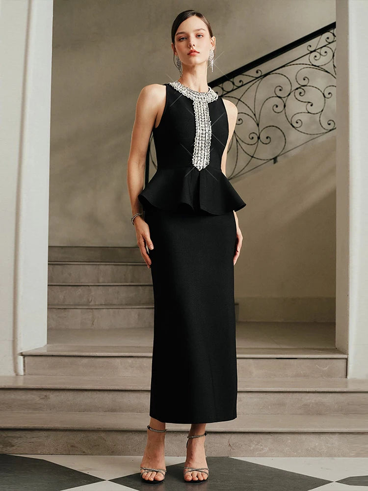 Model wearing a black bandage midi dress with a crystal embellished O-neckline, standing on elegant stairs in a refined interior setting.