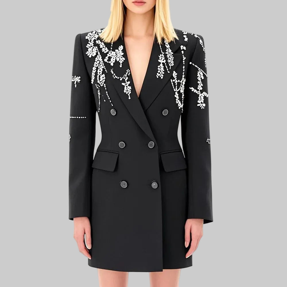 Model wearing a black double-breasted coat dress with diamond-style lapel embellishment, photographed against a clean studio background.