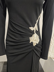 Close detail of the crystal floral embellishment at the hip on a black gown, highlighting the sculpted drape and gathered waist