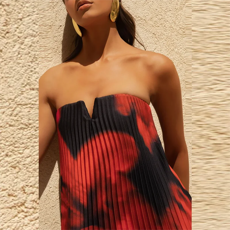 Woman wearing a Red and  Black floral strapless maxi outfit for warm summer evenings against a textured beige wall.