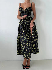  A woman wearing a black floral V-neck maxi dress with a side slit against a white background.