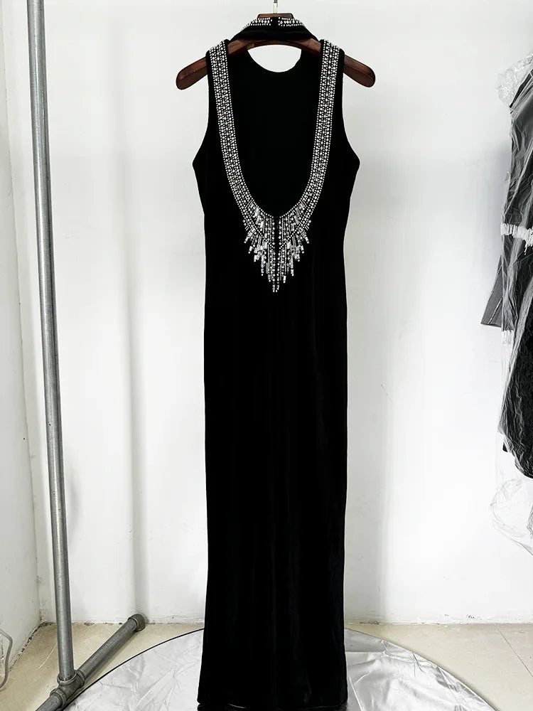 A black floor-length halter dress with a deep open back and slim silhouette.