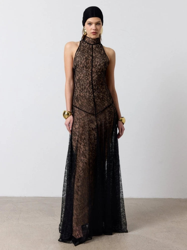 Model wearing a black high-neck sleeveless lace maxi dress on a plain backdrop, styled with statement jewelry for an evening look.