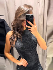 Close, angled mirror shot showing a black high-street halter top with sculpted texture paired with dark bottoms.