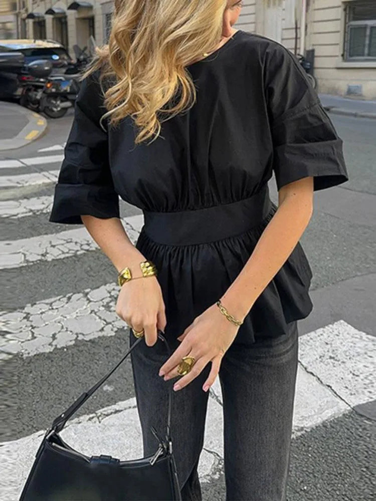 Person wearing a black outfit with a city street background