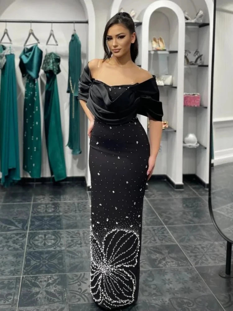 Women wearing a black off shoulder crystal bodycon gown styled for an evening event standing in a store.