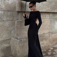 Close-up highlighting the open-back cut and delicate chain detail on a black evening gown, with smooth knit fabric hugging the waist.