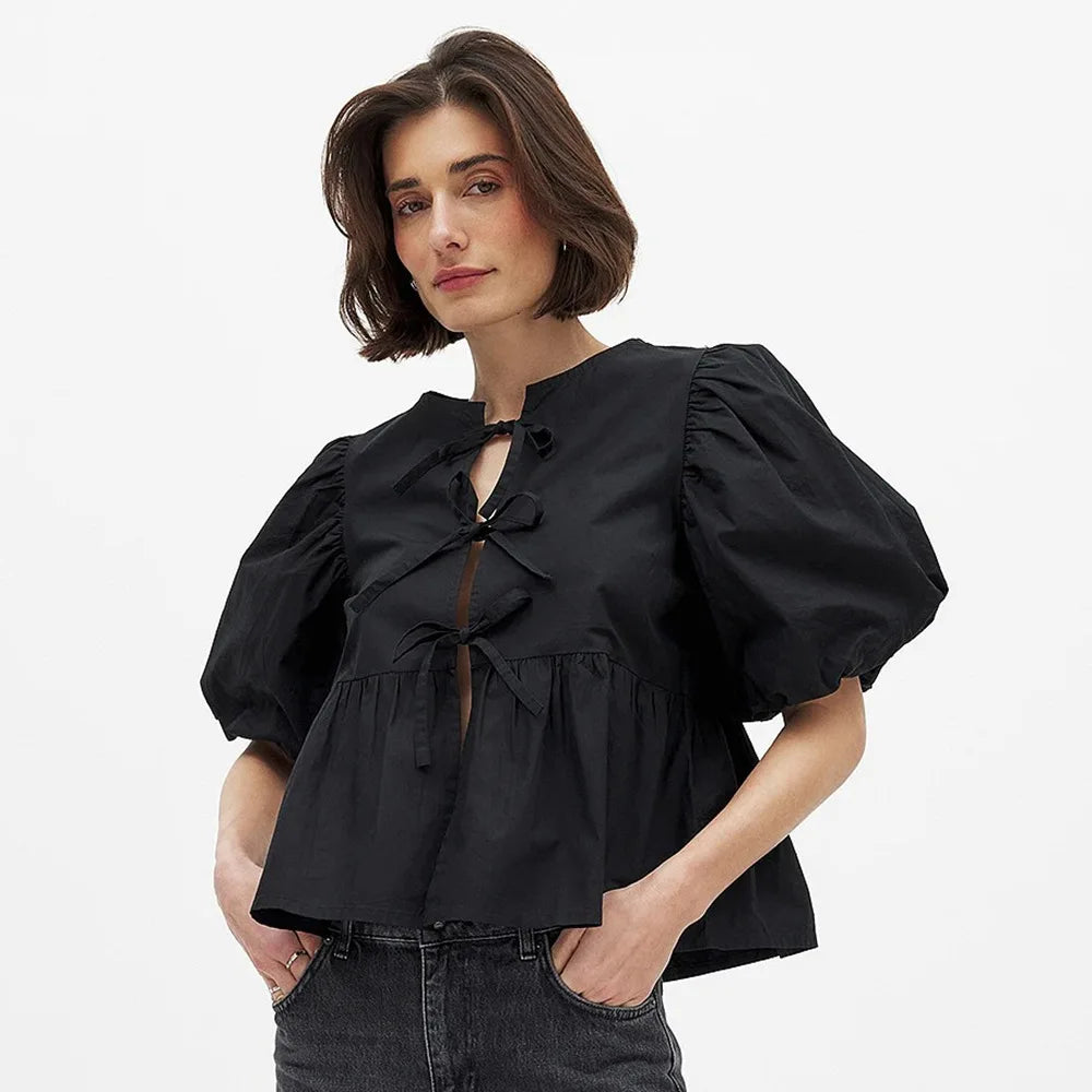 Front waist view of a black blouse showing gathered peplum shape and gentle drape through the torso for an easy, polished look.