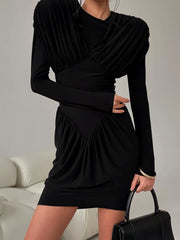 Person wearing a black mini dress with draped pleated bodice and long sleeves