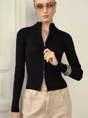 Black ribbed zip-up sweater paired with beige pants and minimal accessories .