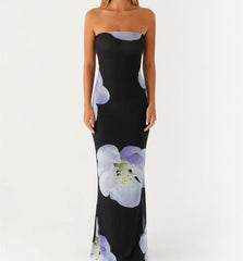 Woman in black strapless floral maxi dress standing against white backdrop
