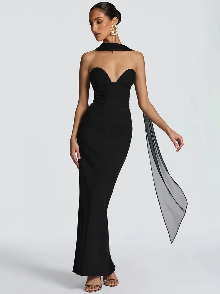 Woman wearing a black strapless gown with a long train on a light gray background