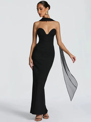 Woman wearing a black strapless gown with a long train on a light gray background