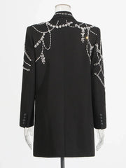 Black tailored coat dress displayed straight on, emphasizing structured shoulders, long sleeves, and refined proportions.